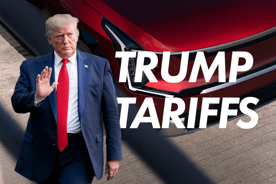 U.S. President Donald Trump walking and waving, dressed in a navy suit, white shirt, and red tie. In the background, the front grille of a red Kia vehicle is partially visible. Bold white text overlays the image, reading “TRUMP TARIFFS,” indicating a discussion about automotive tariffs during his 2025 presidency.