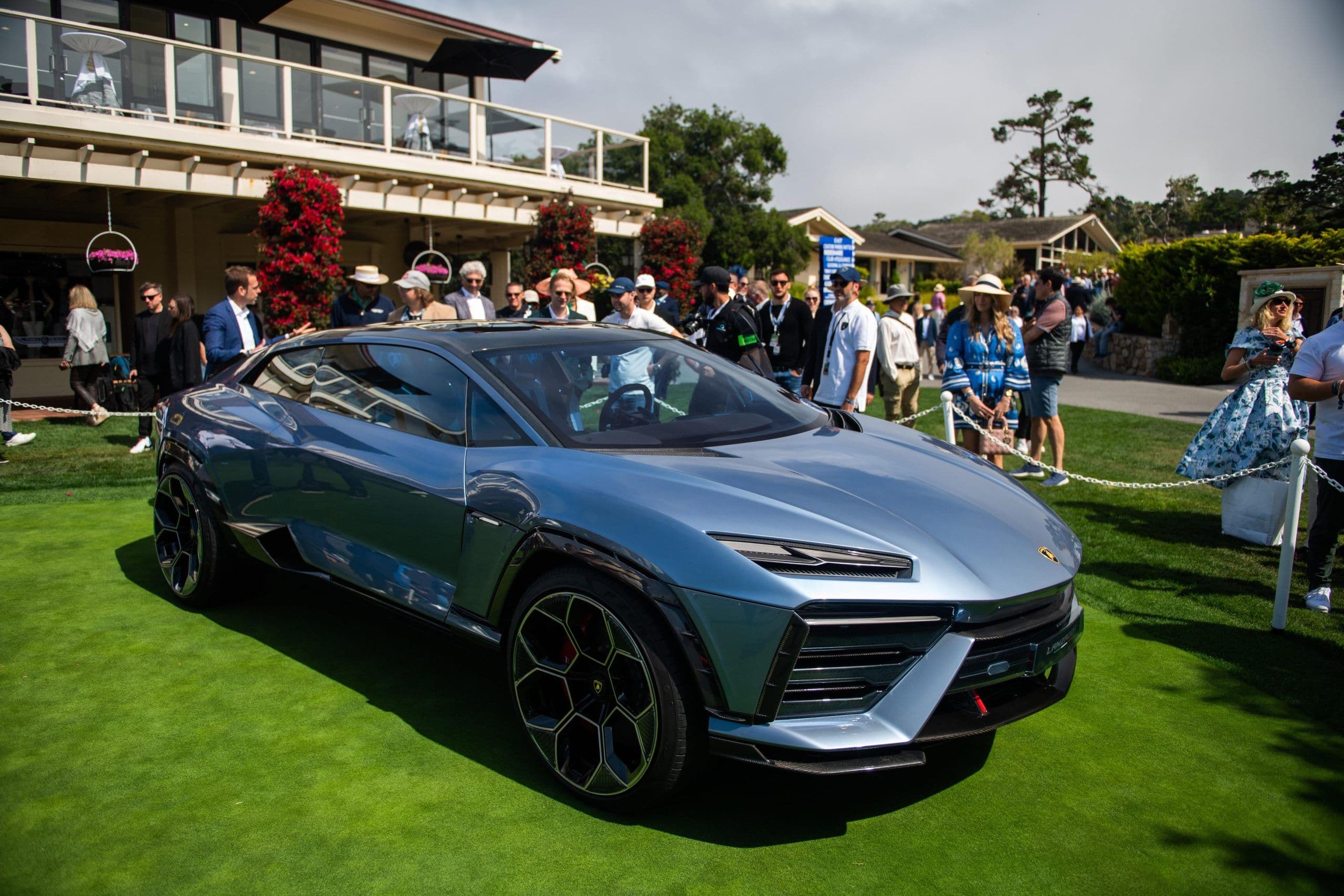 The Lamborghini Lanzador electric concept car on display at the Pebble Beach Concours d’Elegance, surrounded by an elegantly dressed crowd and set against a picturesque backdrop of luxury and greenery.