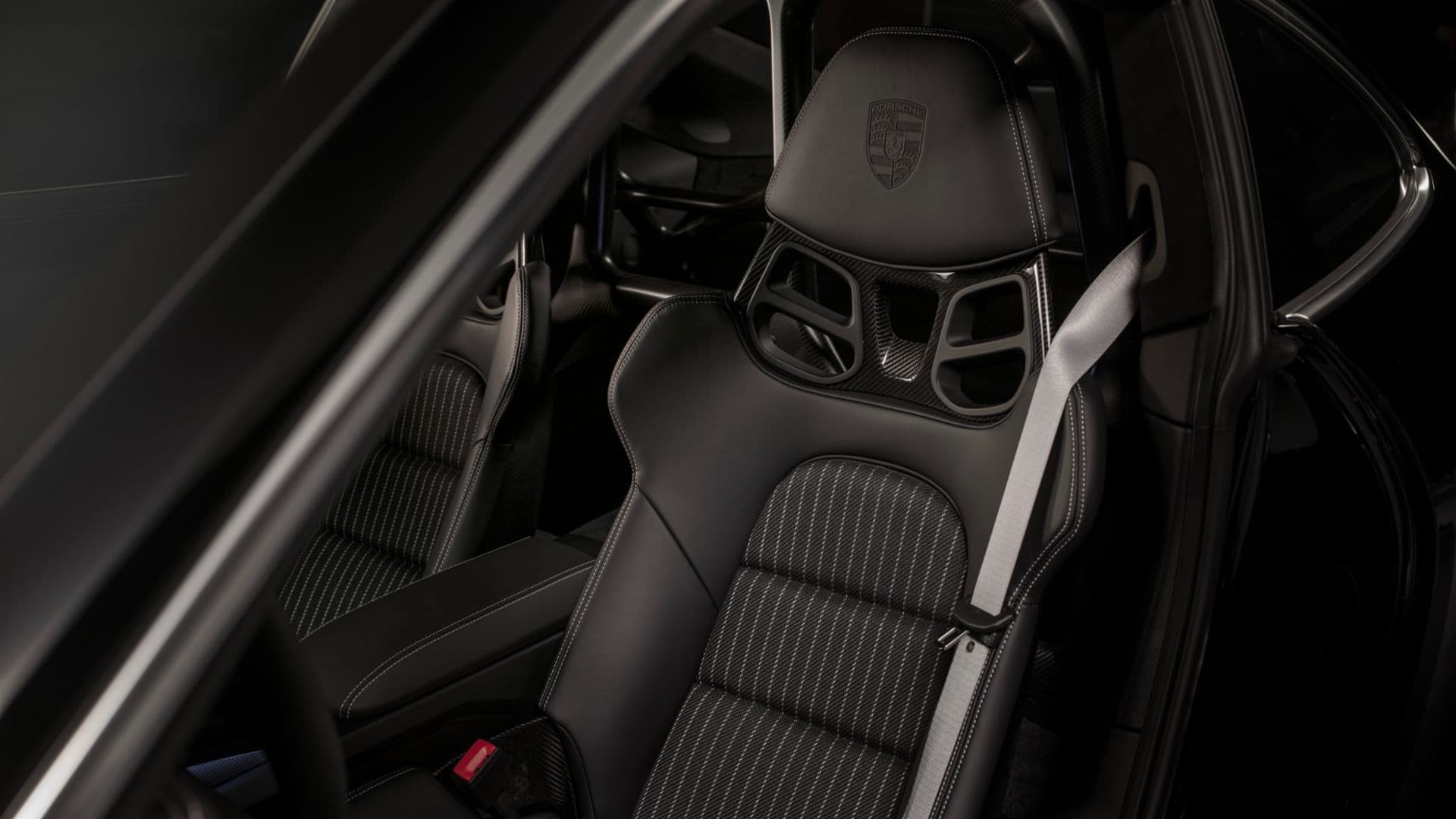Porsche 911 ST carbon fibre bucket seat with embossed crest and grey seatbelt inside the 992 model.