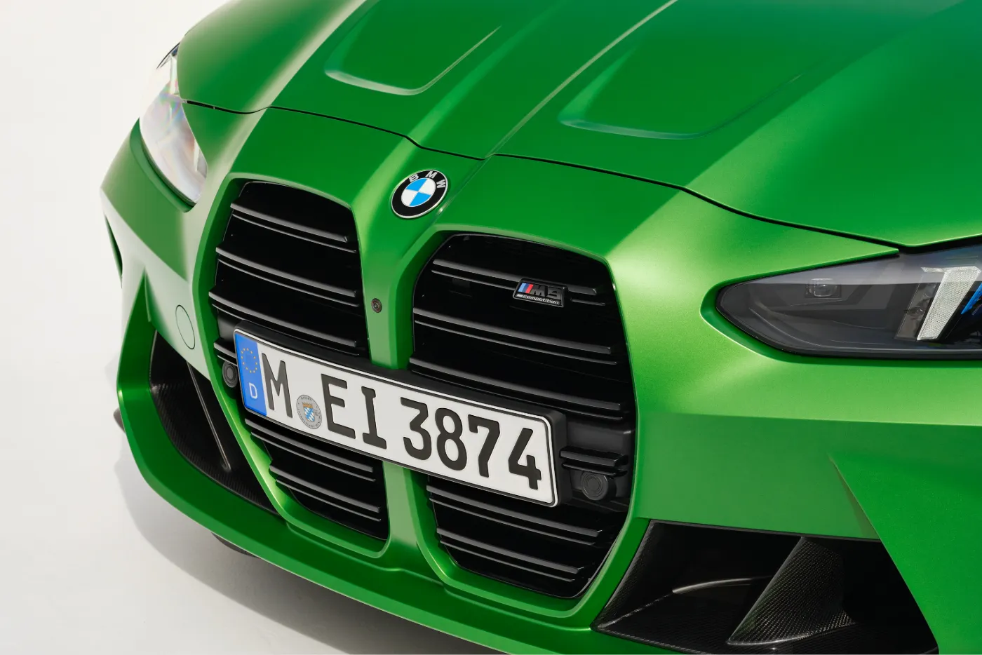 Close-up of the BMW G80 M3 Competition front grille in Isle of Man Green, showing the controversial enlarged vertical kidney grilles and M3 Competition badge.