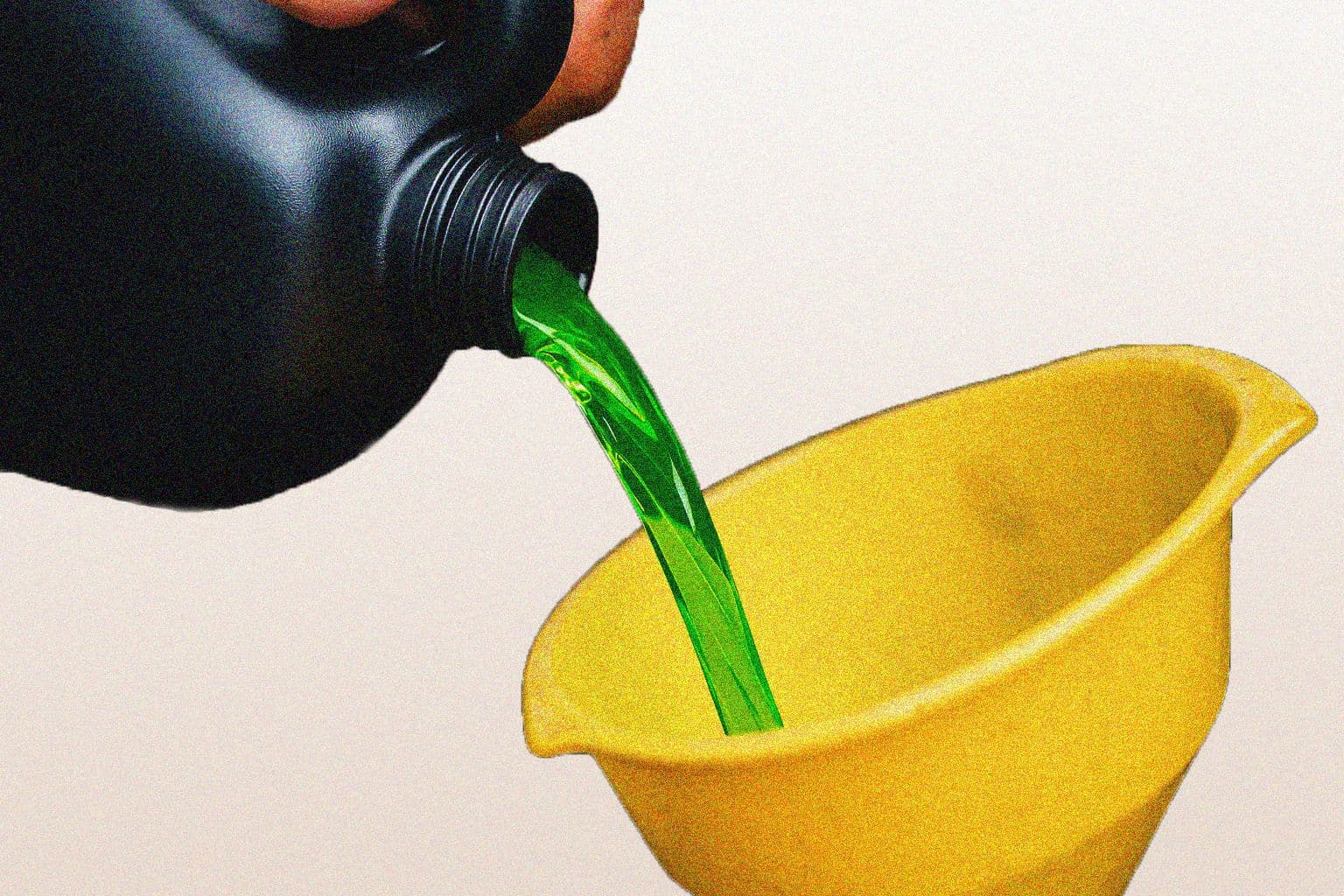 Green engine coolant being poured from a black container into a yellow funnel, against a plain background.