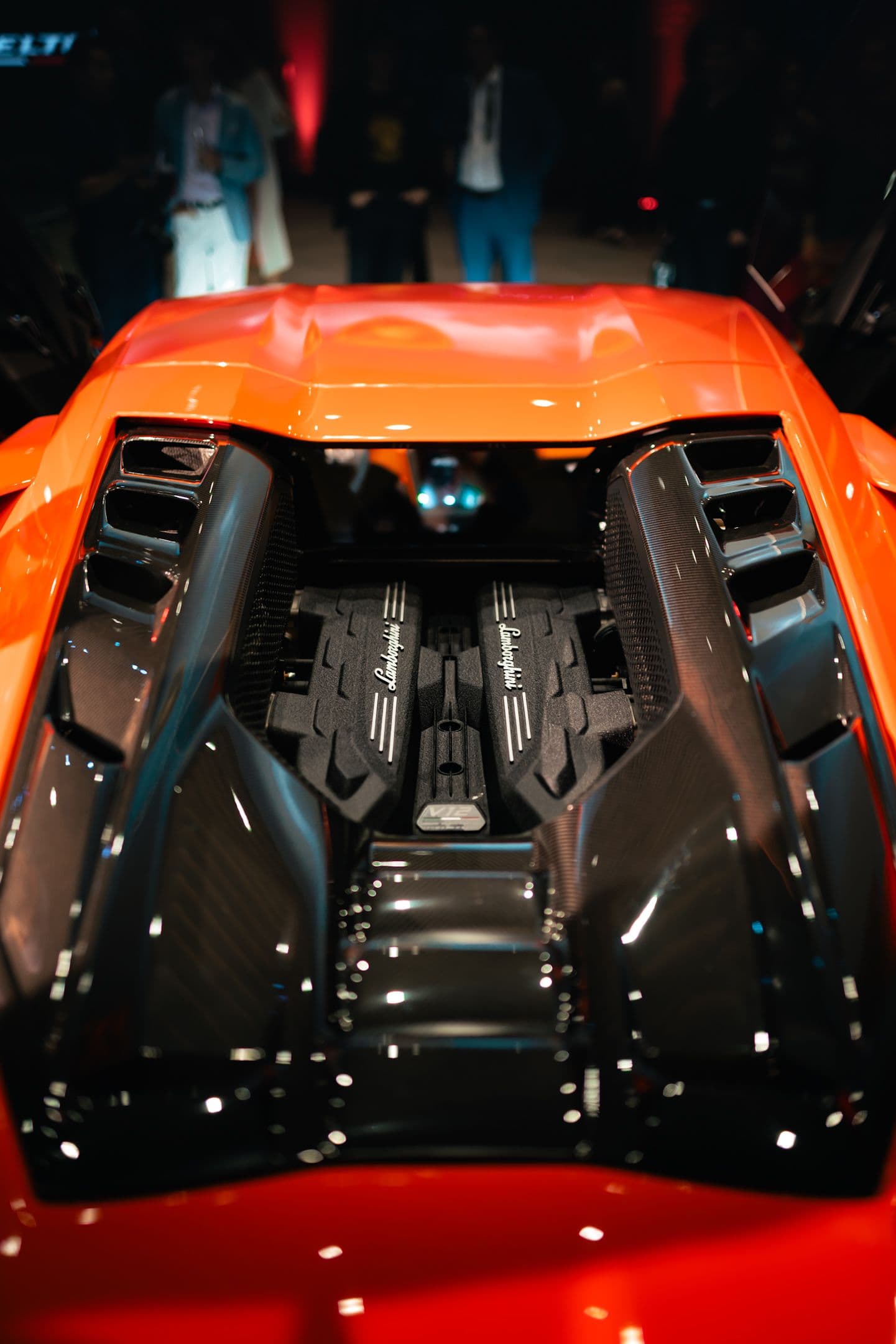 Top view of Lamborghini Revuelto’s naturally aspirated V12 engine with carbon fibre engine bay under show lights.