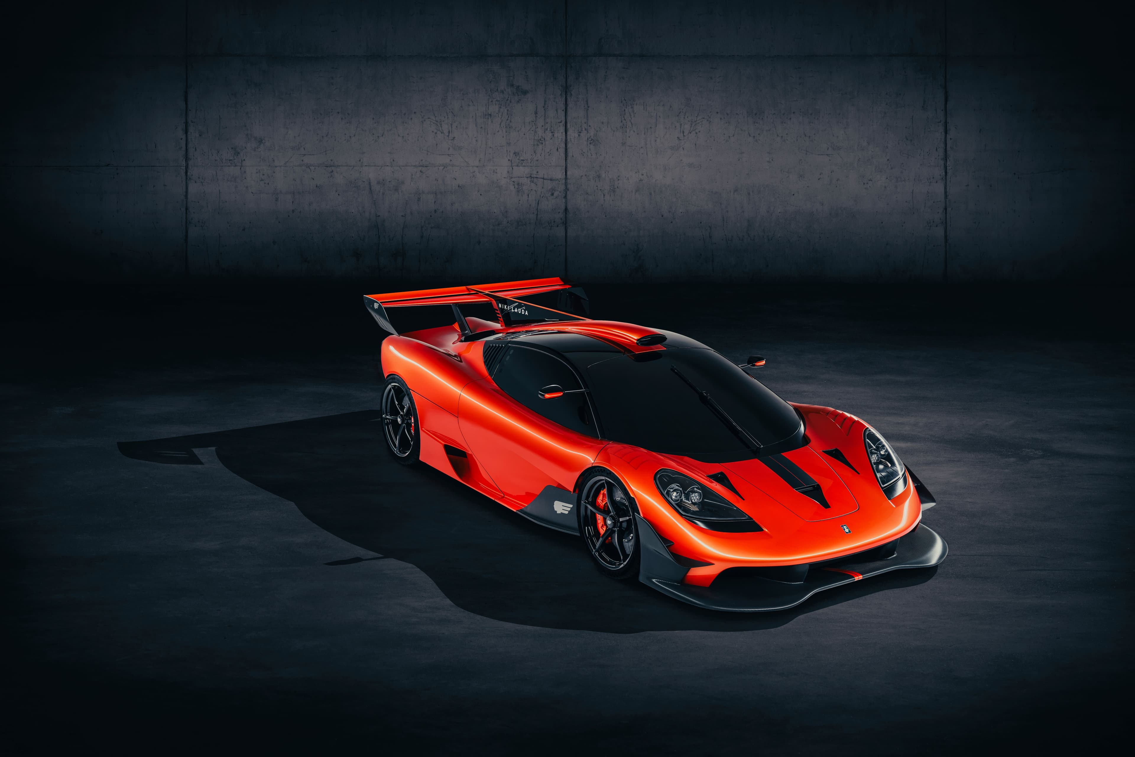 Gordon Murray T.50s Niki Lauda hypercar in red and black livery, photographed in studio lighting with visible aero detailing.