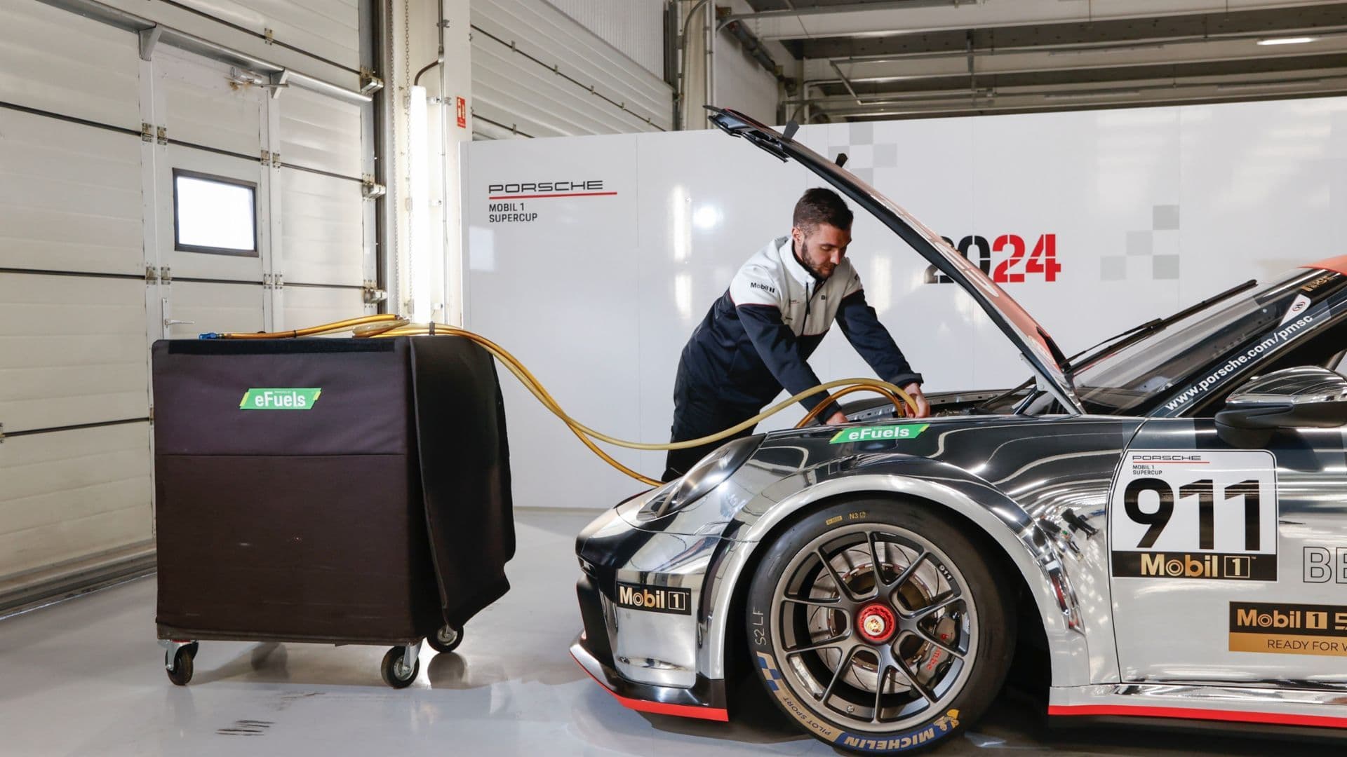 Porsche 911 Mobil 1 Supercup race car being refuelled with eFuels in the garage, showcasing Porsche’s push towards sustainable synthetic fuel in motorsport.