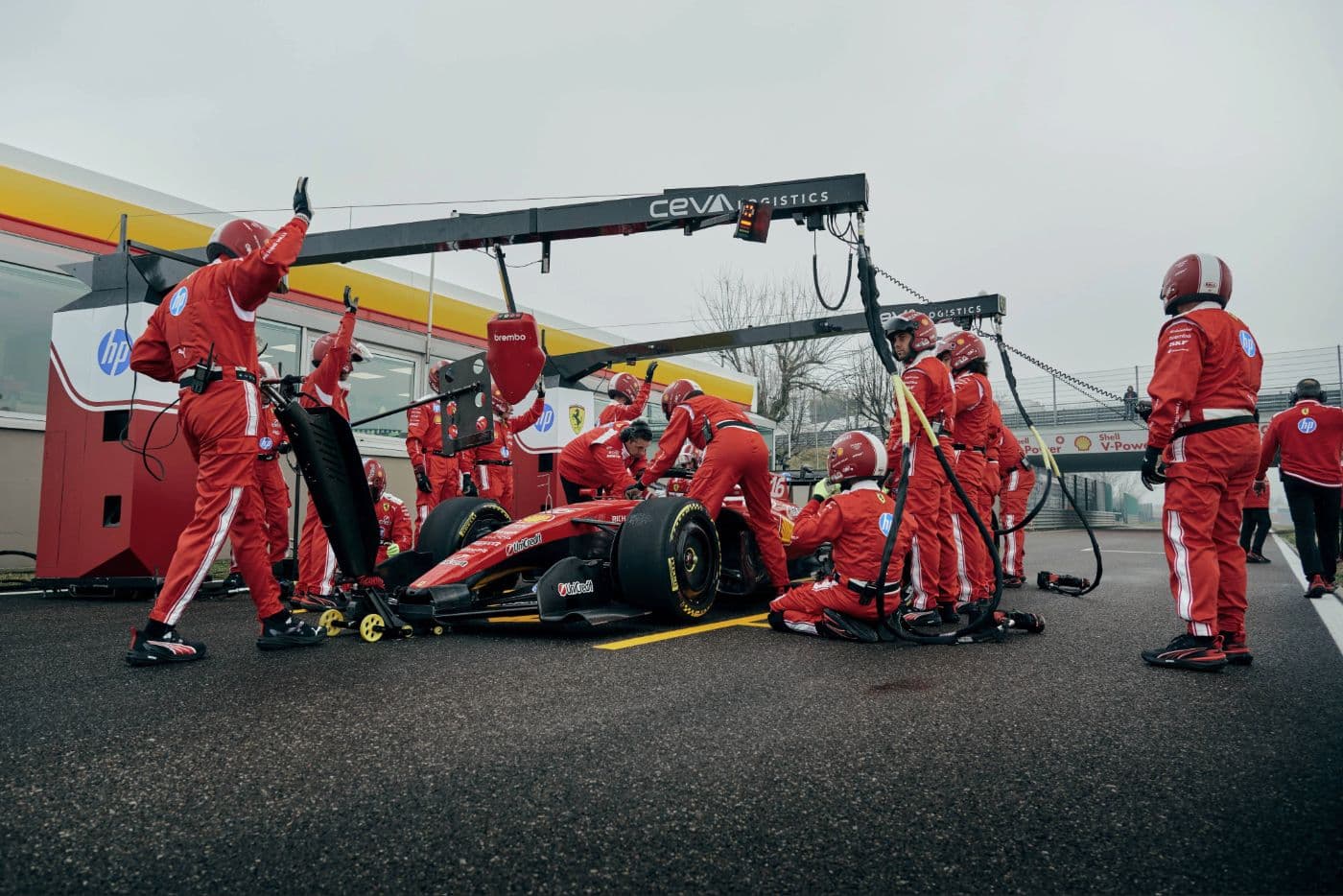 Ferrari SF-26 Formula 1 car surrounded by pit crew during a pre-season pit stop practice session in January 2026, Brembo brake equipment and UniCredit sponsorship visible on the livery