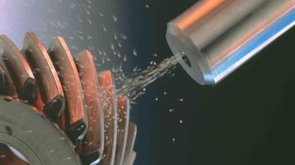 Close-up image of the shot peening process, where metallic particles are being blasted onto a gear surface to improve its fatigue resistance and durability.