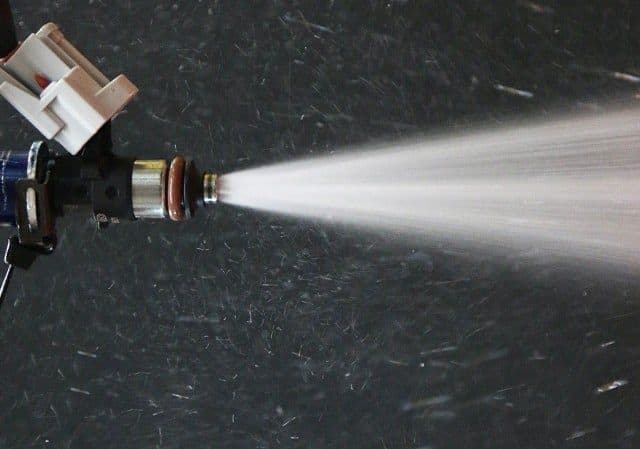 Close-up of a fuel injector spraying a fine atomised fuel mist during spray pattern testing to show flow quality and distribution