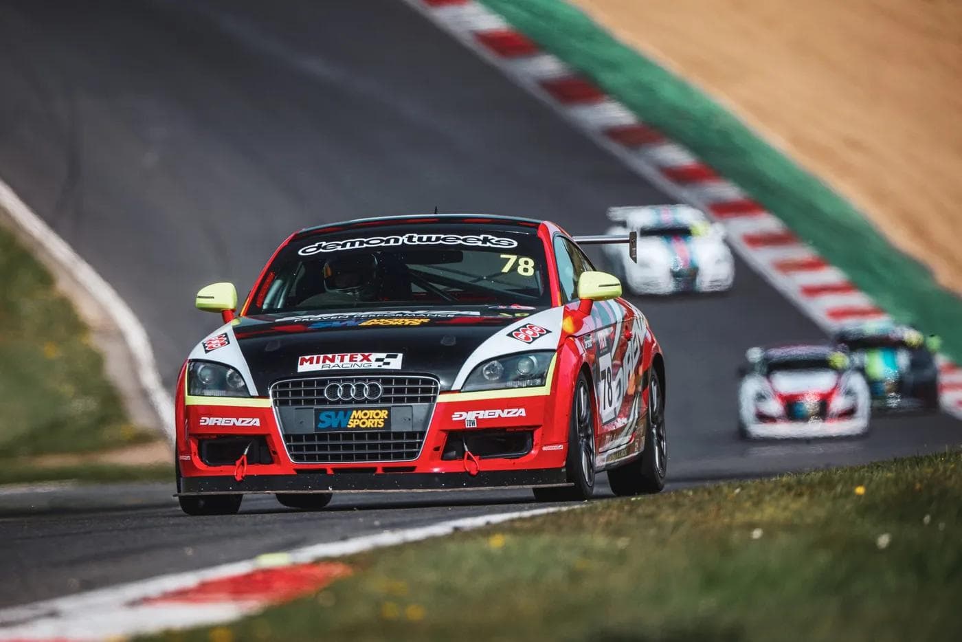 Red Audi TT race car with Direnza performance cooling branding on track, demonstrating motorsport-grade thermal management during competitive driving.