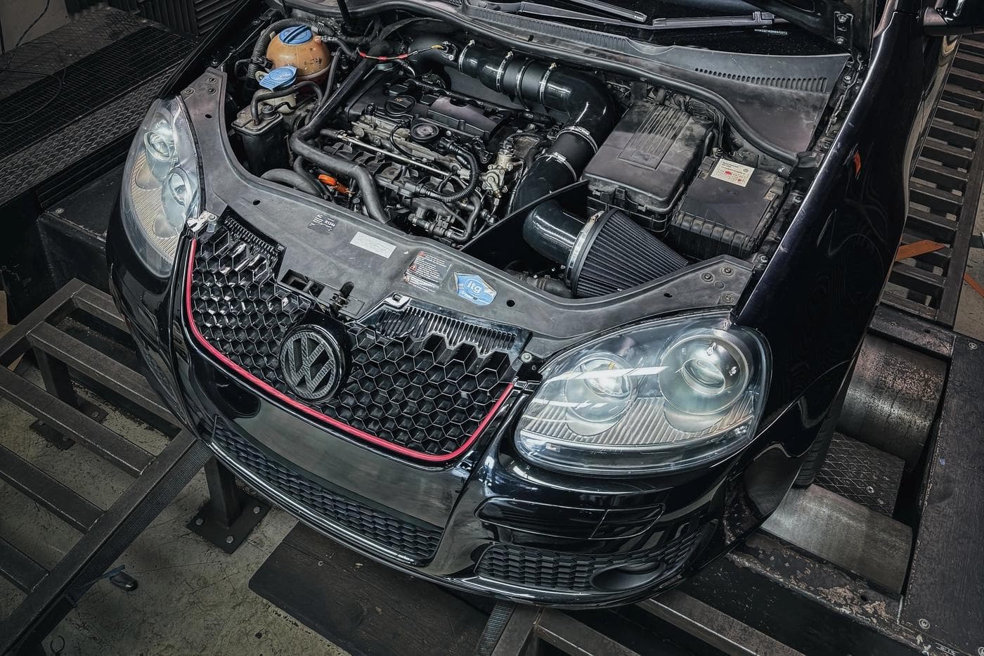 Mk5 Golf GTI EA113 engine bay during dyno testing at JBM Performance, showing turbo installation and cooling system setup for performance tuning.