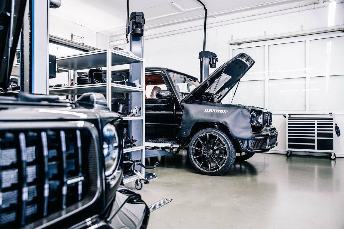 Brabus G63 undergoing performance upgrades in workshop, with branded cover and carbon-fibre components.