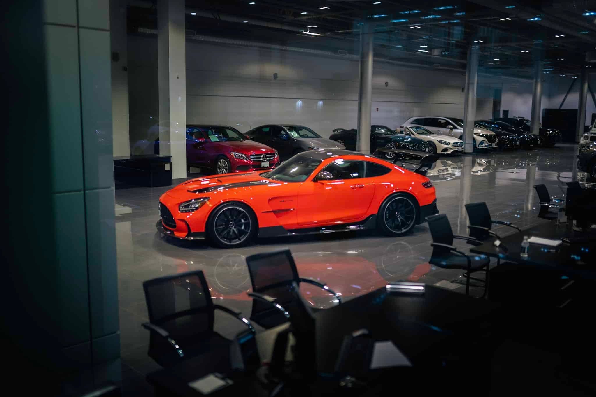 A Mercedes-Benz AMG GT Black Series in Orange inside a car dealership at night