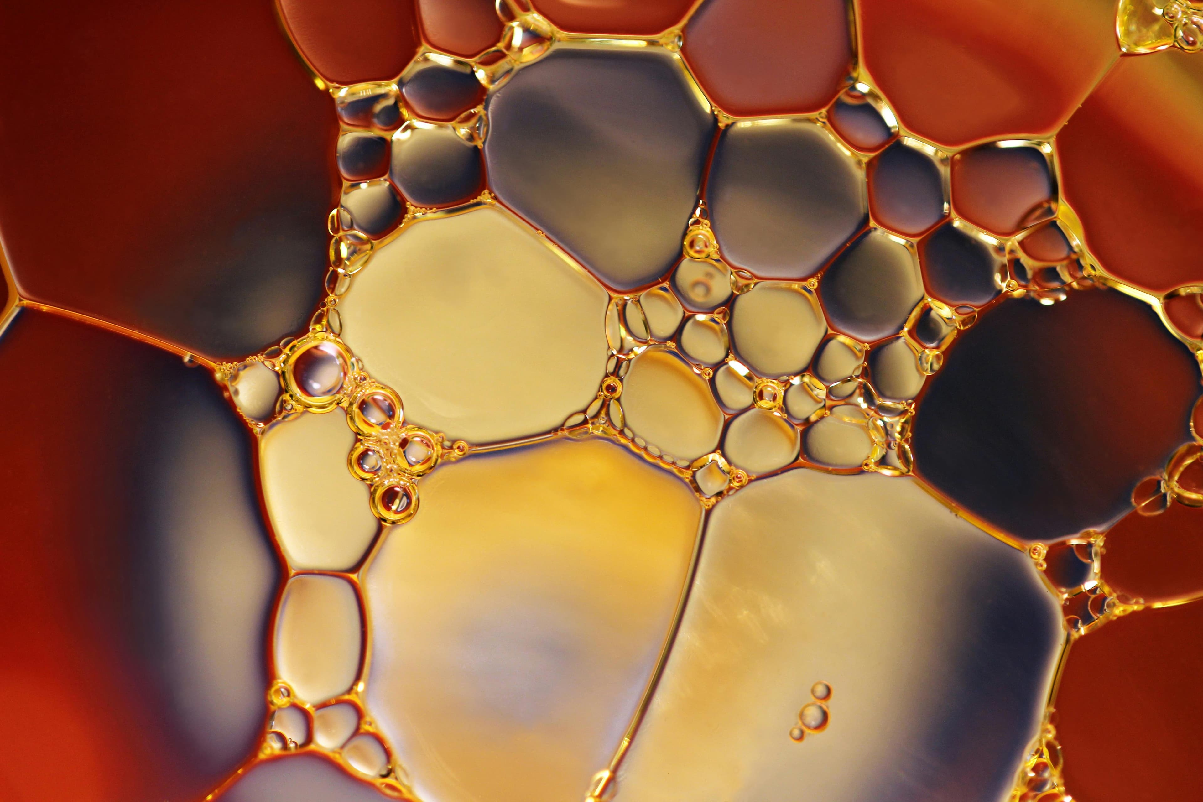 Close-up macro photograph of oil and fuel bubbles, showcasing the molecular interaction of hydrocarbons used in gasoline and lubricants.