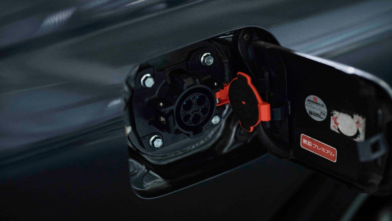 Close-up of the Nissan Skyline R32 GT-R EV charging port, showing detailed electrical connectors inside the retrofitted panel.