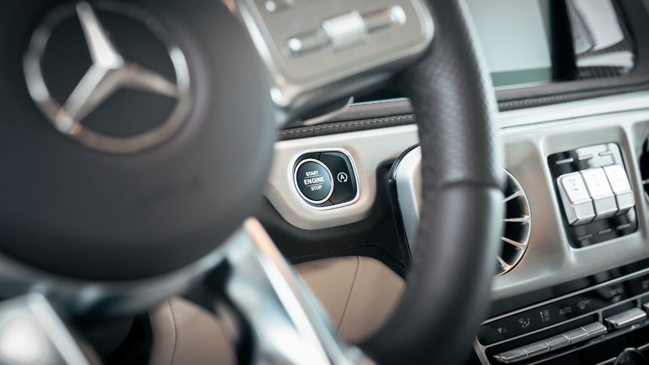 Close-up of Mercedes-Benz G-Class engine start-stop button with premium interior details