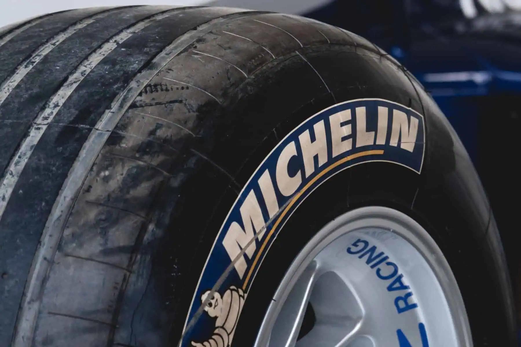 Close-up of a worn Michelin racing slick tyre mounted on a Formula 1-style wheel, showing branding and tire wear.