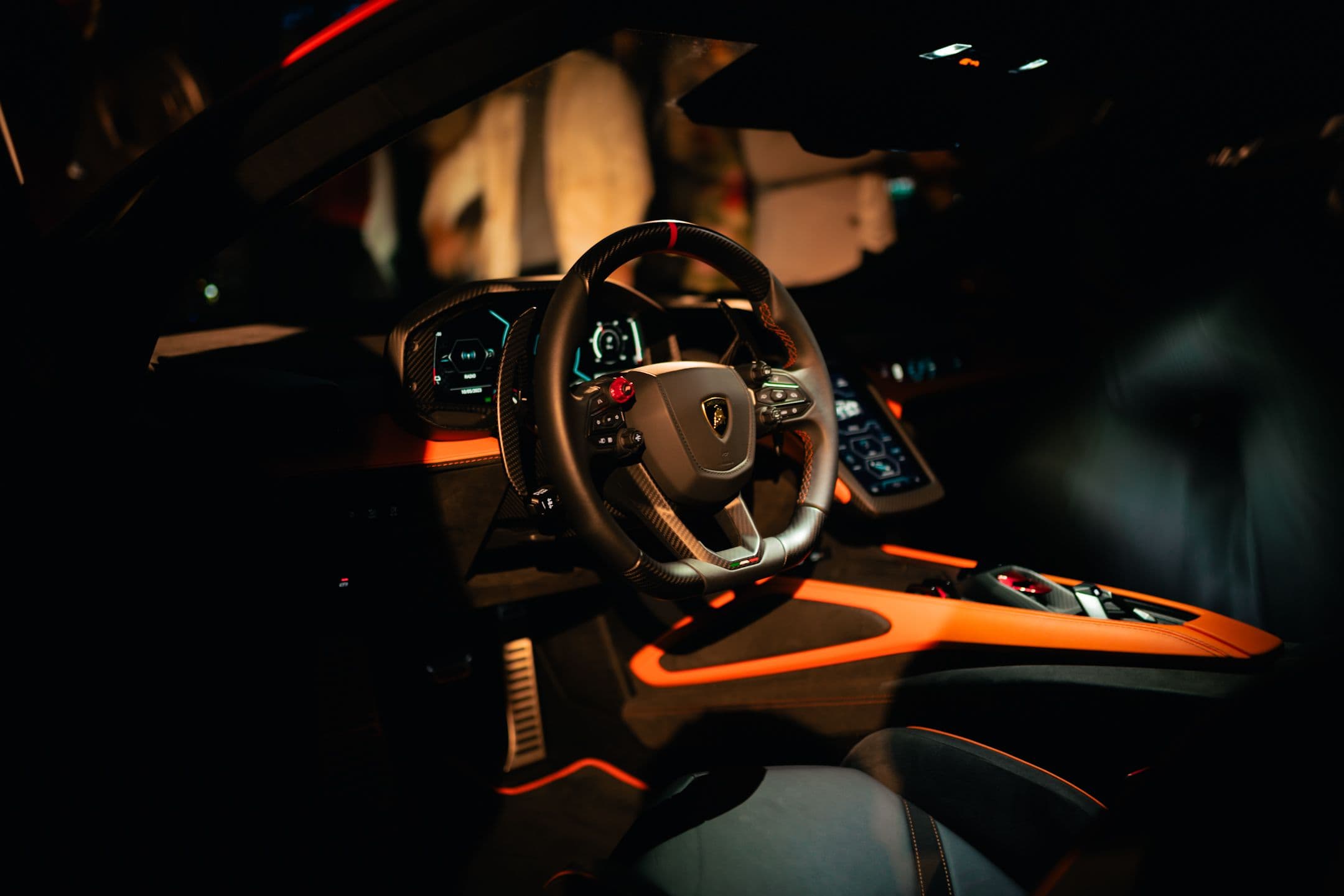 Driver-focused Lamborghini Revuelto interior showing digital cluster, drive mode buttons, and carbon fibre steering wheel.