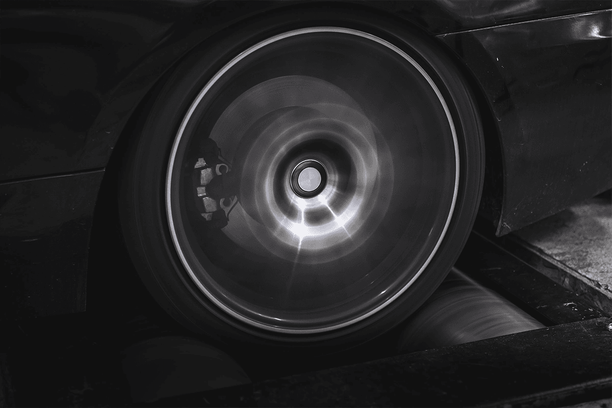 Close-up of a car wheel spinning on a dyno roller during a power run.