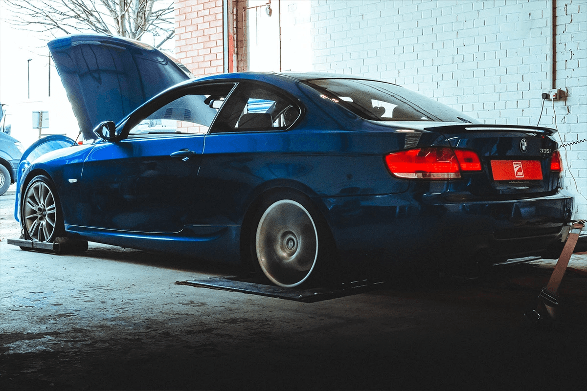 BMW E92 335i with N54 engine on a dyno during a tuning session at JBM Performance, bonnet open and strapped down for testing.
