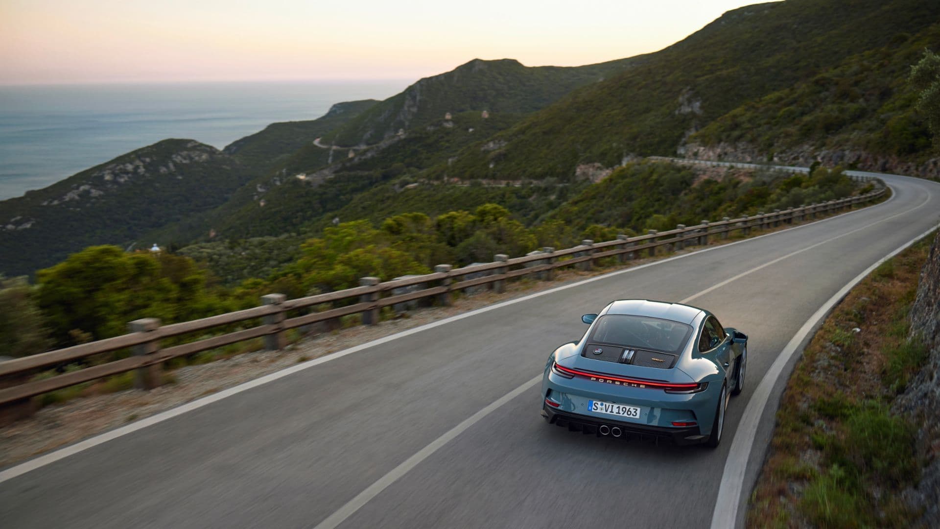 Porsche 911 ST 992 driving through winding hillside road, overlooking scenic coastline.