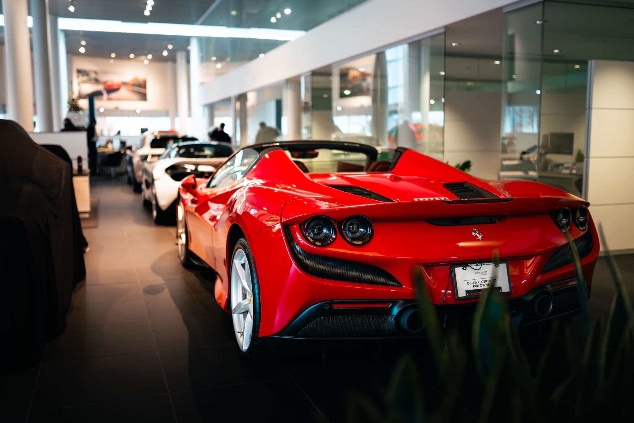 Ferrari F8 Tributo Spider in red on display at a luxury dealership showroom.