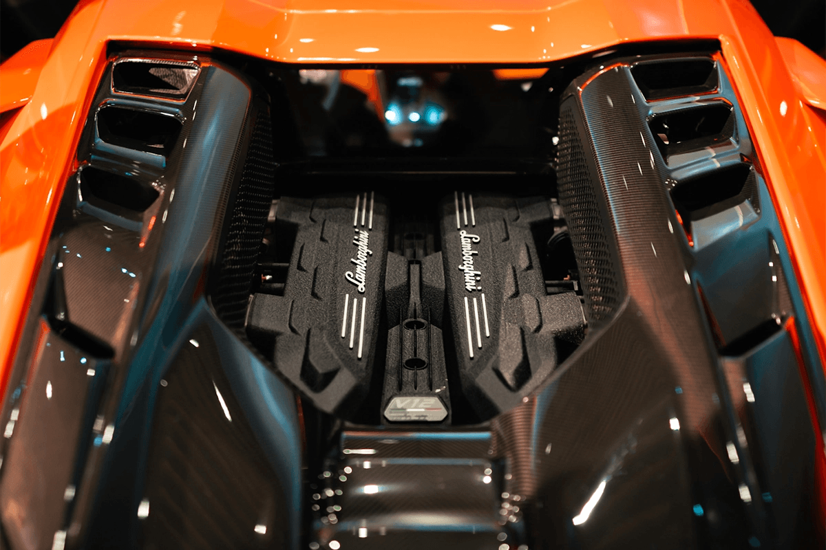 Top view of Lamborghini Revuelto’s naturally aspirated V12 engine with carbon fibre engine bay under show lights.