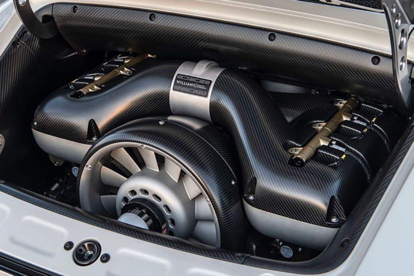 Close-up of a Singer Vehicle Design air-cooled flat-six engine, developed in collaboration with Williams Advanced Engineering, featuring exposed carbon fibre components and a prominent cooling fan.