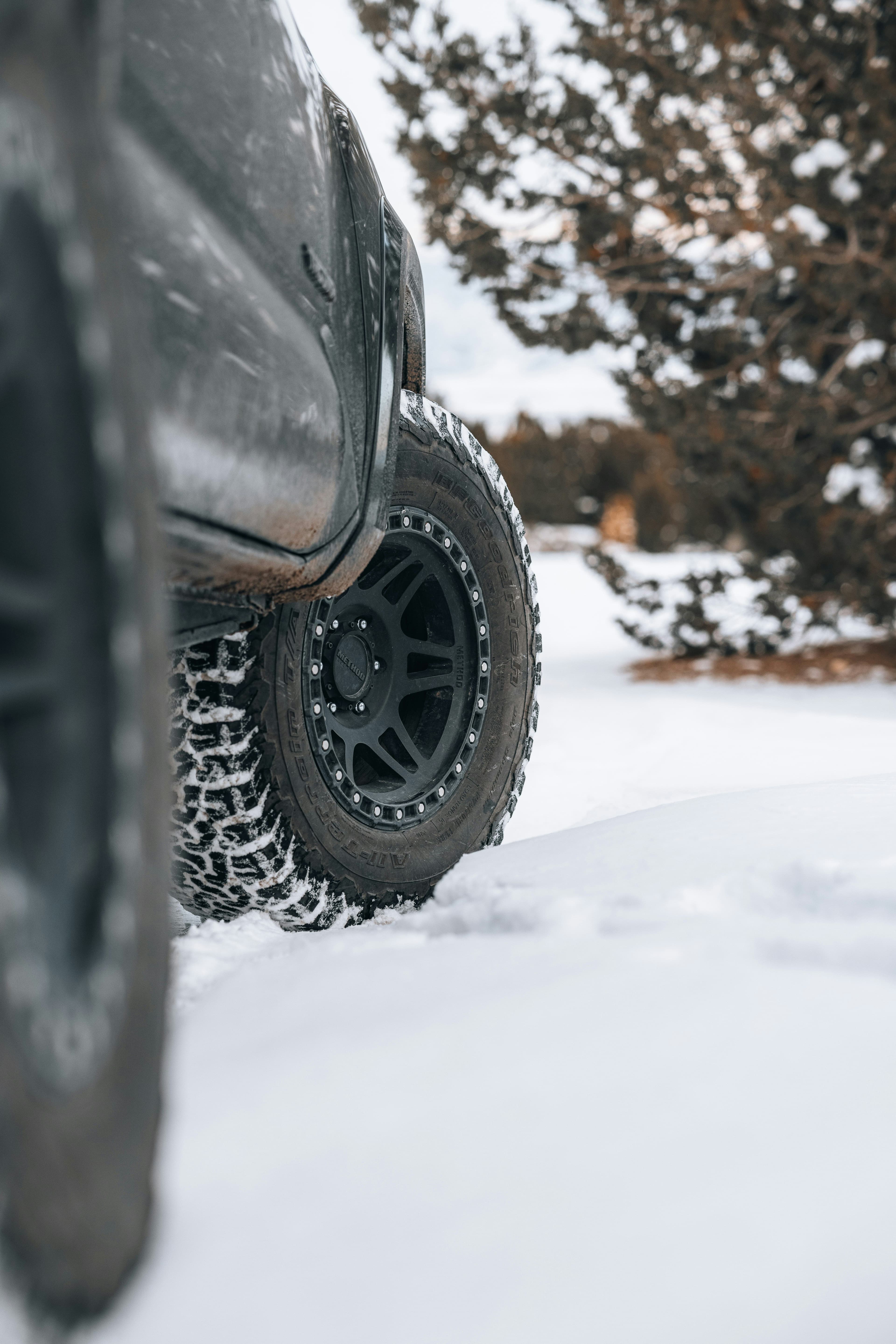 Close-up of an all-terrain tyre on an off-road truck driving through snow-covered terrain